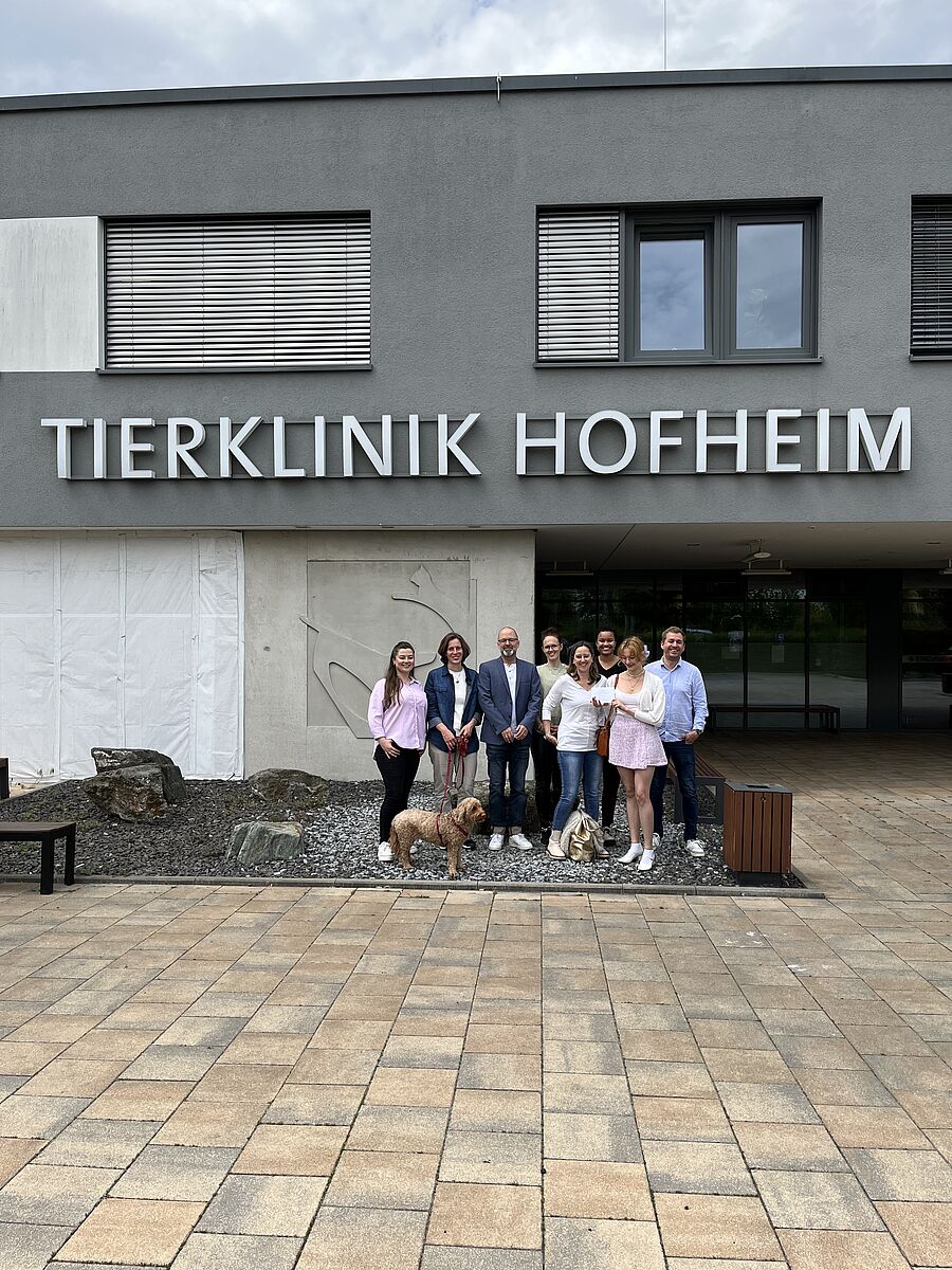 Zwei Mitarbeiterinnen der Klinik und 6 Mitarbeitende von Hauptsache Kommunikation sind von hinten zu sehen, wie sie durch einen Gang durch die Tierklinik Hofheim laufen.