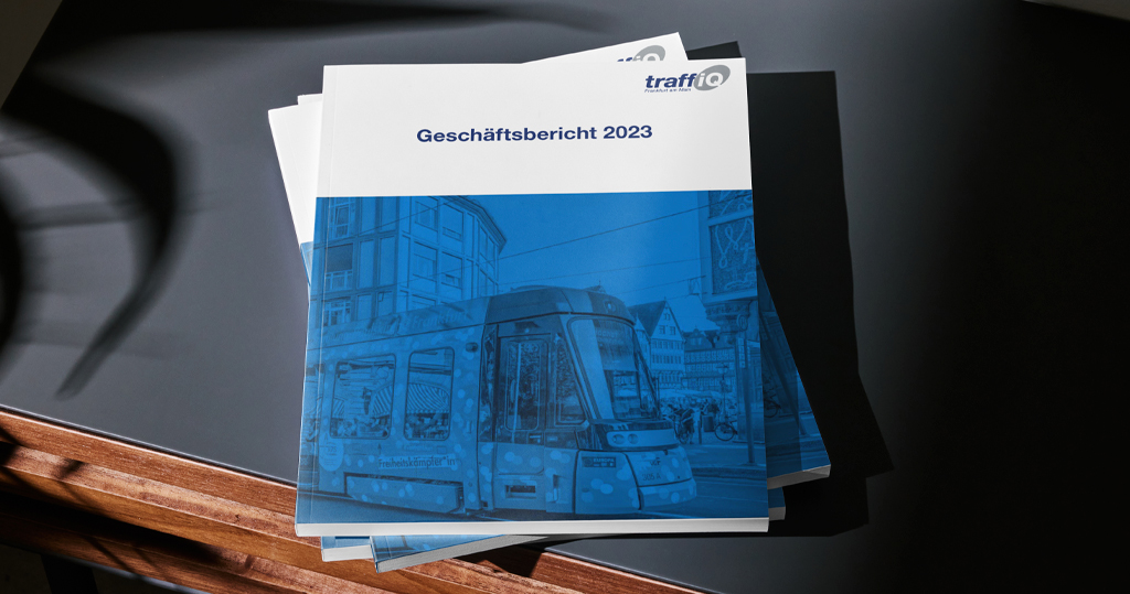 Ein Stapel Geschäftsberichte der traffiQ liegen auf einem Holz-Schreibtisch mit schwarzer Auflage.
