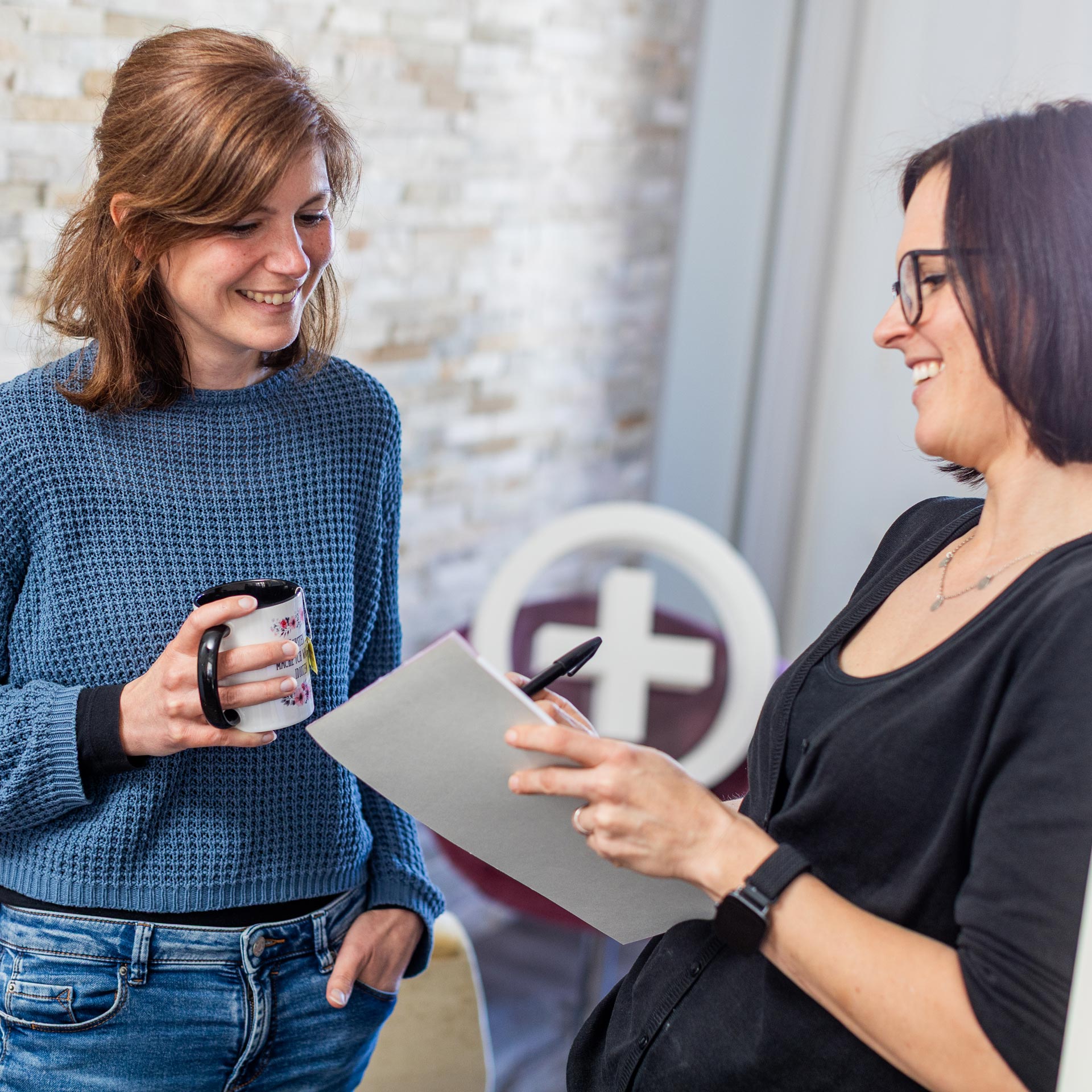 Rebekka und Julia, Redaktion und Grafik, schauen sich gemeinsam einen Block an und reden dabei über ein aktuelles Projekt